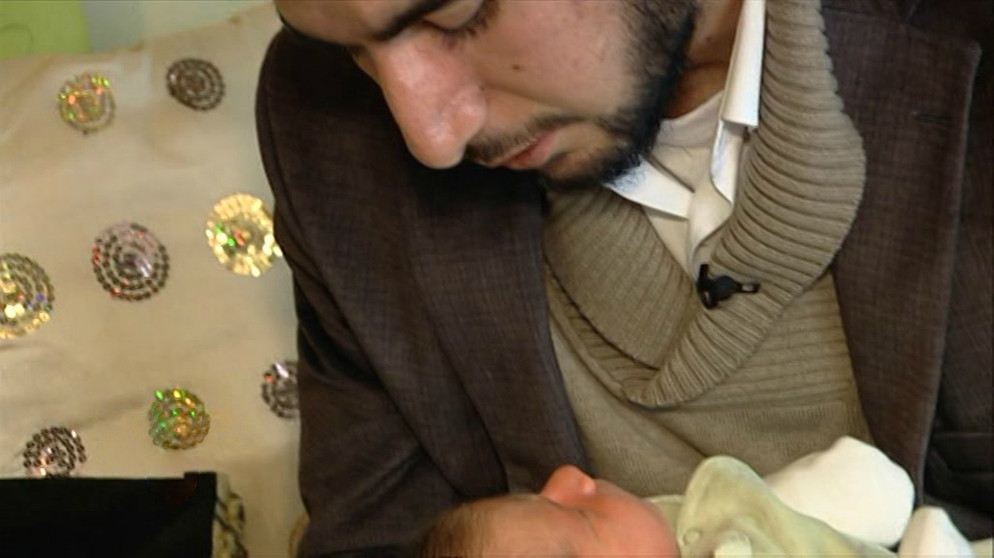Ein Imam hält ein Baby im Arm | Bildquelle: Bayerischer Rundfunk