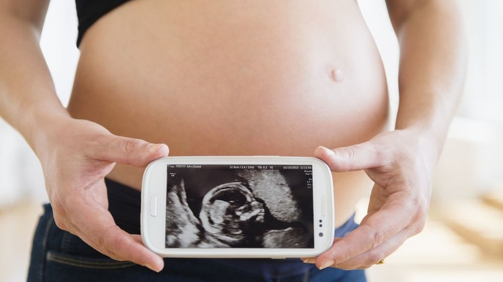 Schwangere zeigt Embryo auf ihrem Smartphone. | Bildquelle: picture-alliance/dpa / Bildagentur-online /Tetra-Images