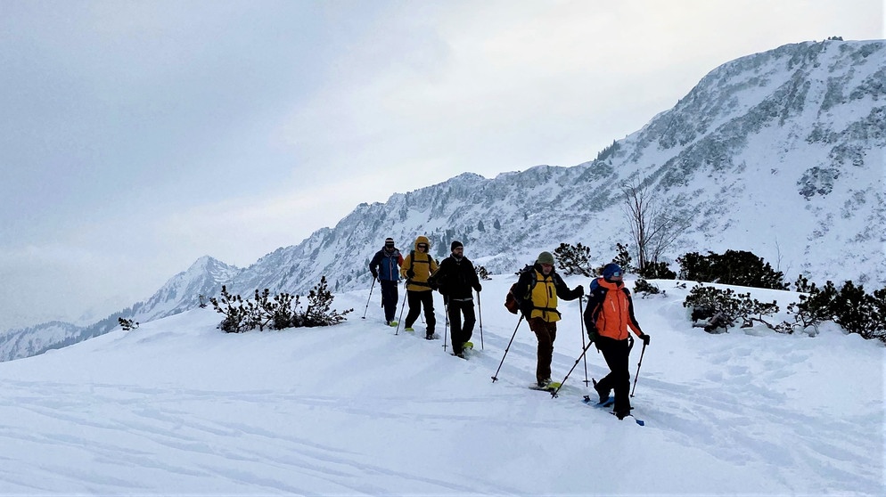 Eine Gruppe Schneeschuh-Wanderern in verschneiter Berglandschaft | Bildquelle: BR/Kathrin Denk