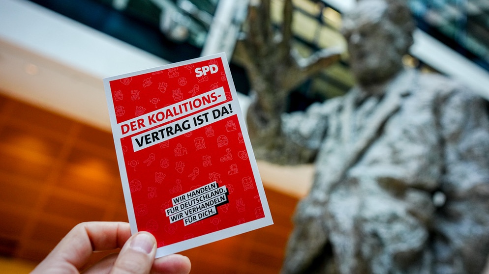Illustration - Eine Werbekarte mit der Aufschrift ·Der Koalitionsvertrag ist da· ist SPD-Parteizentrale, dem Willy-Brandt-Haus, vor der Willy-Brandt-Statue zu sehen.  | Bildquelle: dpa-Bildfunk/Kay Nietfeld