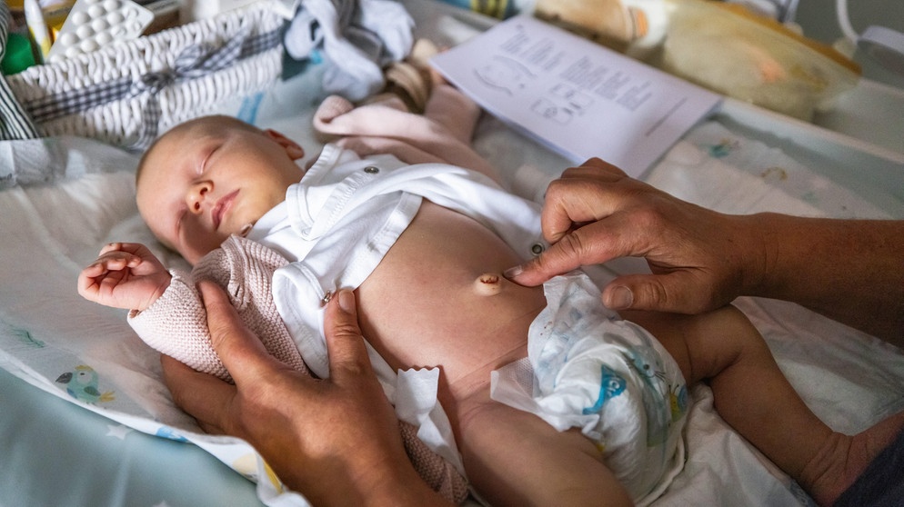 Eine Hebamme kümmert sich im Wochenbett um den Bauchnabel eines Säuglings. | Bildquelle: picture-alliance/dpa