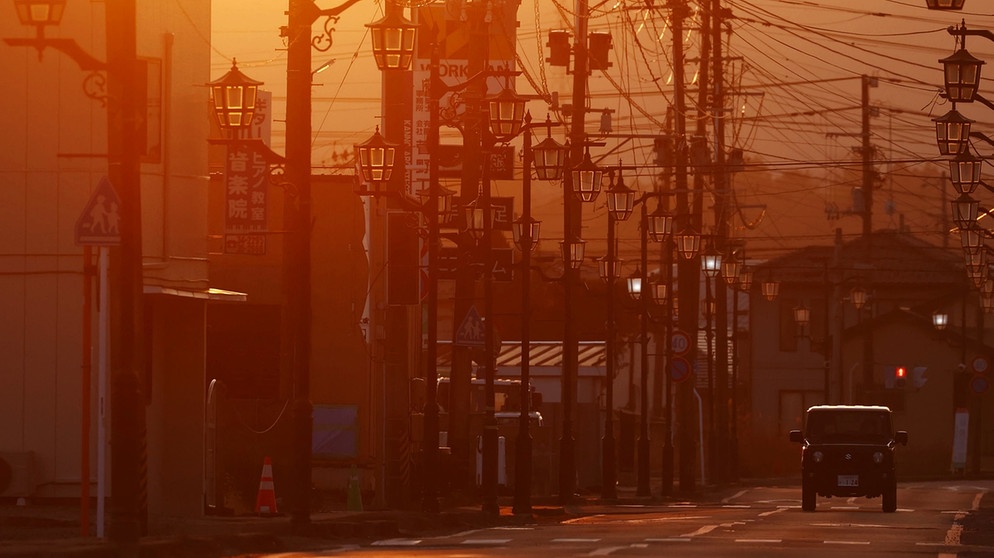 13.02.2021, Japan, Namie: Ein Fahrzeug fährt auf einer menschenleeren Straße in der Präfektur Fukushima. Die Stadt Namie in der Nähe des lahmgelegten Kernkraftwerks Fukushima Daiichi ist auch fast 10 Jahre nach dem Erdbeben menschenleer und der Zugang noch immer eingeschränkt. Am 11. März jährt sich das Unglück zum zehnten Mal. Foto: --/kyodo/dpa +++ dpa-Bildfunk +++ | Bildquelle: dpa-Bildfunk/--
