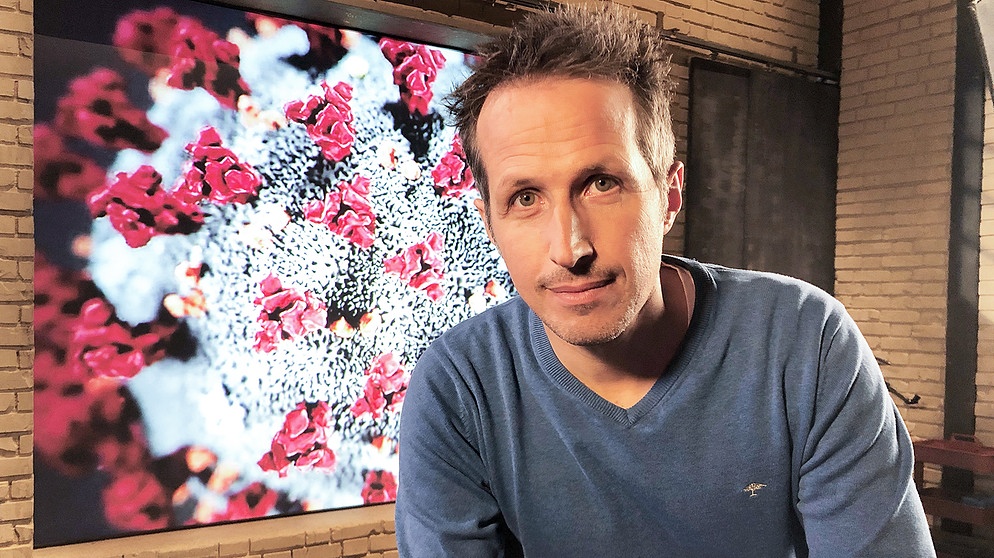 "Gut zu wissen"-Moderator Willi Weitzel mit Corona-Virus Grafik im Hintergrund. In dieser Sendung gehts u.a. um das Thema Corona-Impfung für Kinder. | Bildquelle: BR/Gut zu wissen