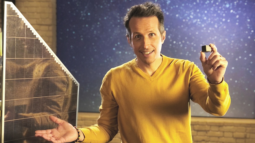 "Gut zu wissen"-Moderator Willi Weitzel hält einen kleinen Teil "Weltraumschrott" in der Hand. In der Sendung fragt er nach, wie Müll im Weltall beseitigt werden kann.  | Bildquelle: BR/Gut zu wissen