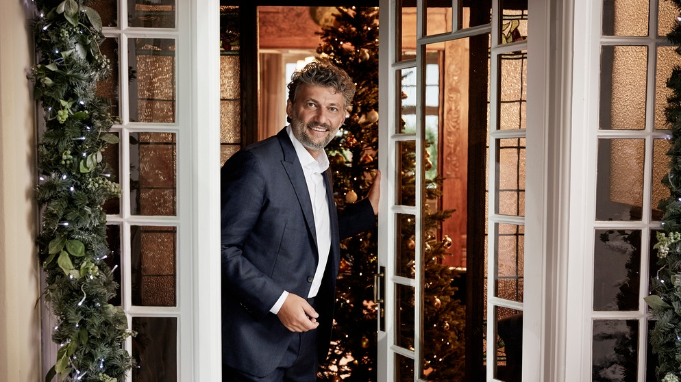 Jonas Kaufmann öffnet die Tür eines weihnachtlich geschmückten Hauses | Bildquelle: Gregor Hohenberg / Sony Classical