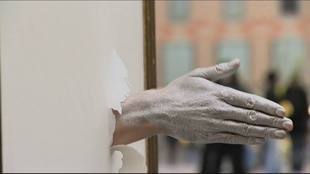 Hand greift durch einen Papierbogen | Bildquelle: Bayerischer Rundfunk