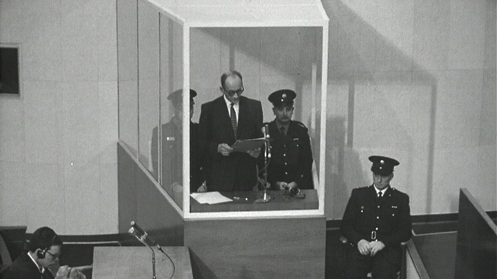 Adolf Eichmann im Glaskasten mit drei Polizisten, Verteidiger Dr. Robert Servatius und sein Assistent (links). | Bildquelle: BR